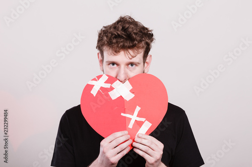 Sad man with glued heart by plaster. photo