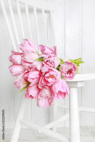 Bouquet of pink tulips lying on a chair.