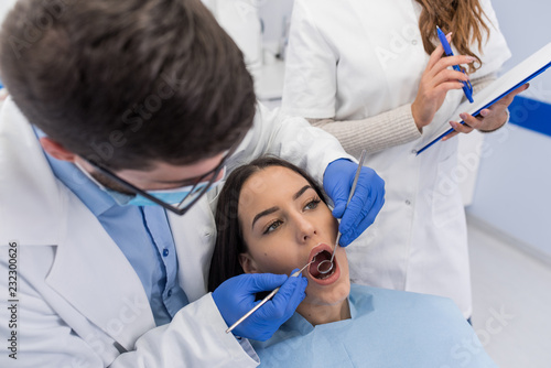 High angle view of dentist examining girl with dental equipments