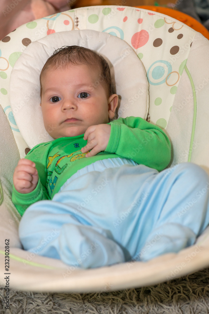 The newborn lies on swing automatic electrical chair and enjoys it The newborn lies on swing automatic electrical chair and enjoys it