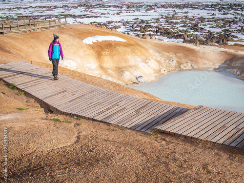 Tourist girl walking near the sulfur springs at Leirhnjúkur, near the Krafla Vulcano, Iceland photo