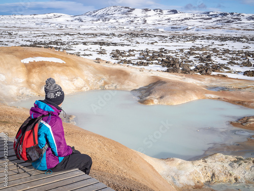 Tourist girl sitting near Sulfur springs at Leirhnjúkur, near the Krafla Vulcano, Iceland photo