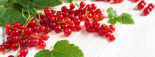 Berries of juicy red currant and leaves on a light wooden background. The pattern with copy space is flat lay