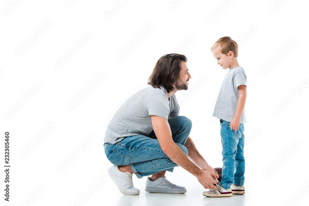 Caring father helping his son to tie shoelace isolated on white Caring father helping his son to tie shoelace isolated on white