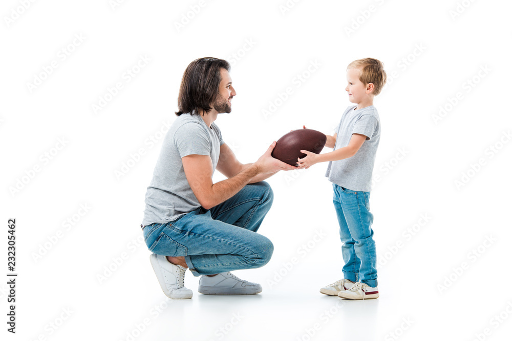 Caring father giving american football ball to his son isolated on white Caring father giving american football ball to his son isolated on white