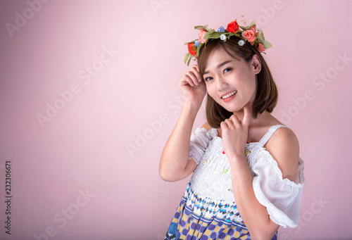 Asian girl with acne-free face and freckles ,Which is the problem of teens.Young woman pose on a pink background and in the hand holding a beautiful bouquet.