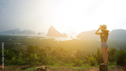 Thailand Pangnga 3 Nov 2018, a female traveler wearing a floral shirt, is taking a photo of herself with mountain and sea views in Phang Nga Province, Thailand.