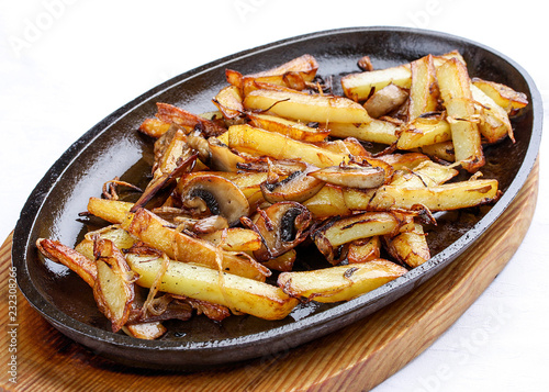 Fried potatoes with onions and mushrooms. On a cast-iron frying pan.