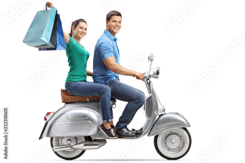 Young male and female riding on a vintage motorbike with shopping bags