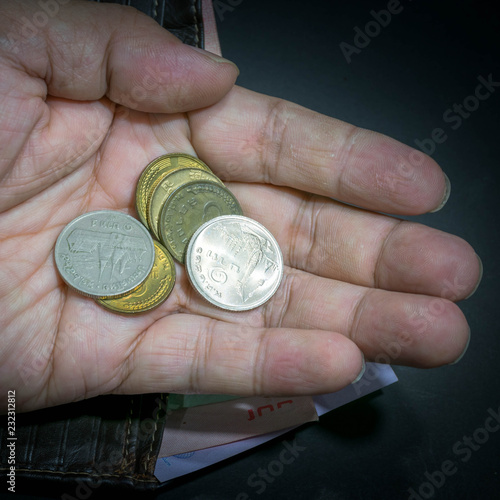 Many coins in the hand and have banknotes in the wallet as a background.