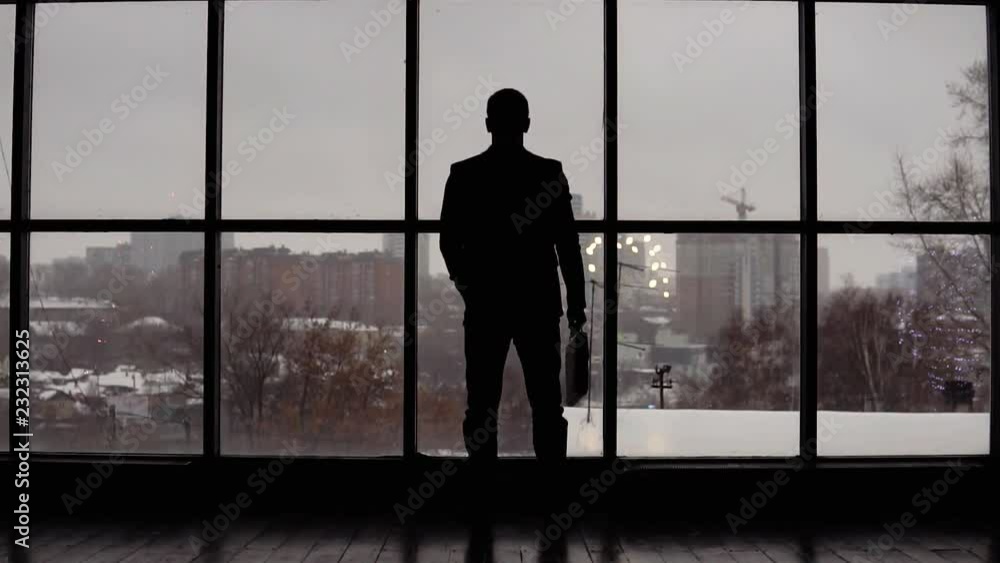 businessman looks time on wrist watch in office near window businessman looks time on wrist watch in office near window