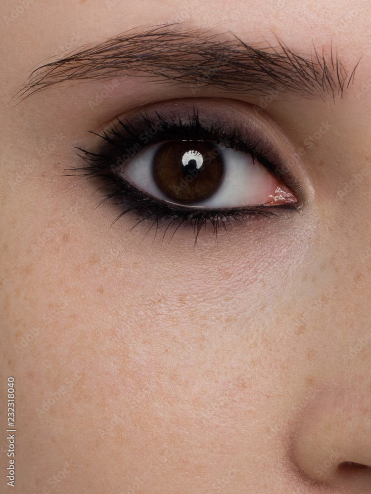 Obraz premium Elegance close-up of female eye with classic dark brown smoky make-up. Macro shot of woman's face part. Beauty, cosmetics and makeup.