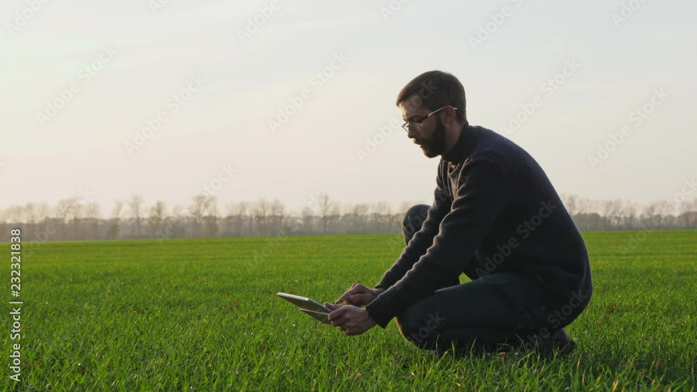 A farmer makes a photo in a winter wheat field with a digital tablet A farmer makes a photo in a winter wheat field with a digital tablet