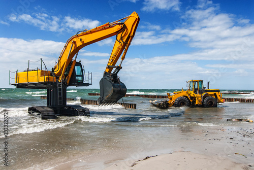 excavator and bulldozer on the beach, building groynes