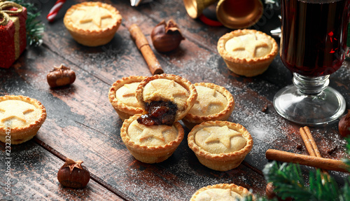 British Christmas mince pies with decoration, gifts, green tree branch on wooden rustic table