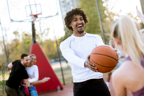 Multiracial couple playing basketball on outdoor court