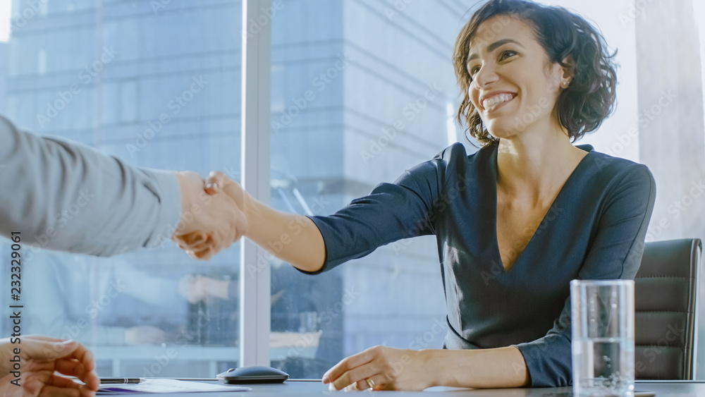 Obraz premium Beatiful Young Businesswoman Talks with a Potential Business Partner and Shakes Hands When them come to a Agrement. Strong Independent Woman in Business Situation.