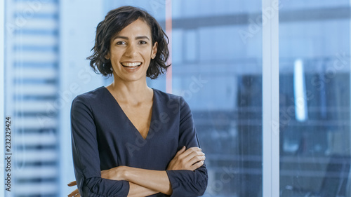 Portrait of the Successful Businesswoman Crossing Her Arms and Smiles. Beautiful Woman Executive Standing in Her Office. photo