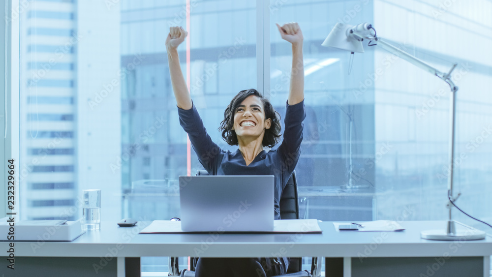 Shot of the Beautiful Businesswoman Sitting at Her Office Desk, Raising Her Arms in a Celebration of a Successful Job Promotion. - obrazy, fototapety, plakaty 