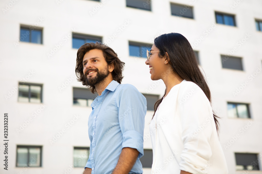 Obraz premium Happy professional managers walking at office building in city. Attractive businesswoman and handsome businessman walking together on street . Colleagues concept