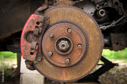 rusty brake disc and pad on a broken car in the yard