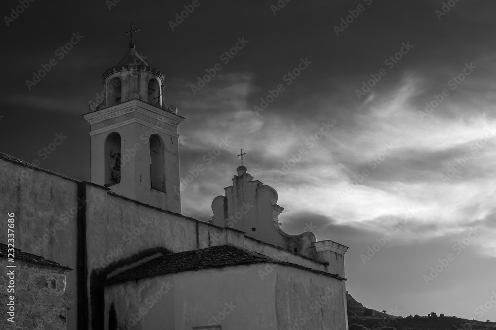 Alter Kirchturm im Gegenlicht mit Wolken in schwarz weiß