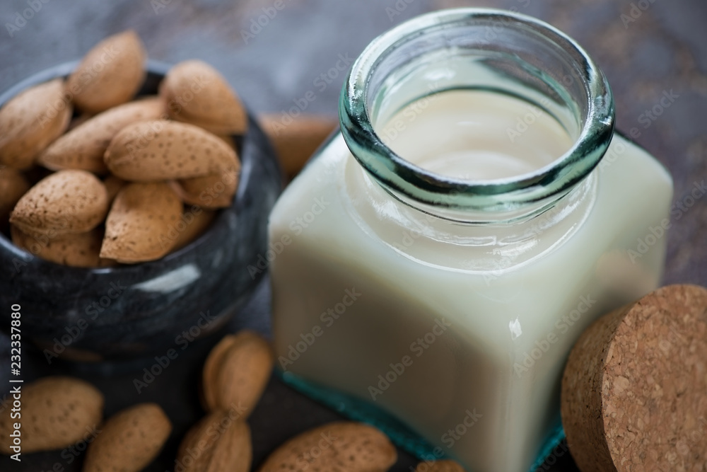 Closeup of a glass jar with almond milk and unpeeled almonds, selective focus, studio shot Closeup of a glass jar with almond milk and unpeeled almonds, selective focus, studio shot