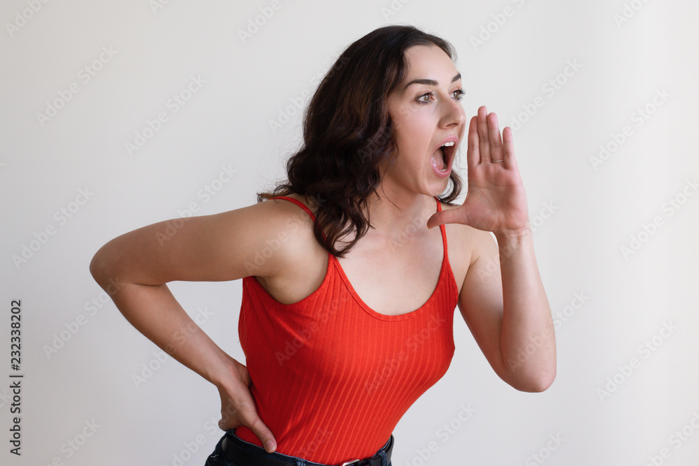Energetic Caucasian girl making megaphone shape with hand and shouting aside. Young female startuper spreading information about her business. Advertising campaign concept Energetic Caucasian girl making megaphone shape with hand and shouting aside. Young female startuper spreading information about her business. Advertising campaign concept