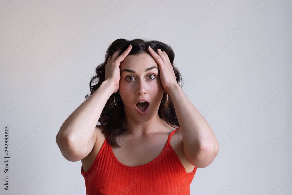 Shocked pretty Caucasian girl gripping head with both hands. Young manager shouting with wide eyes. Deadline concept Shocked pretty Caucasian girl gripping head with both hands. Young manager shouting with wide eyes. Deadline concept