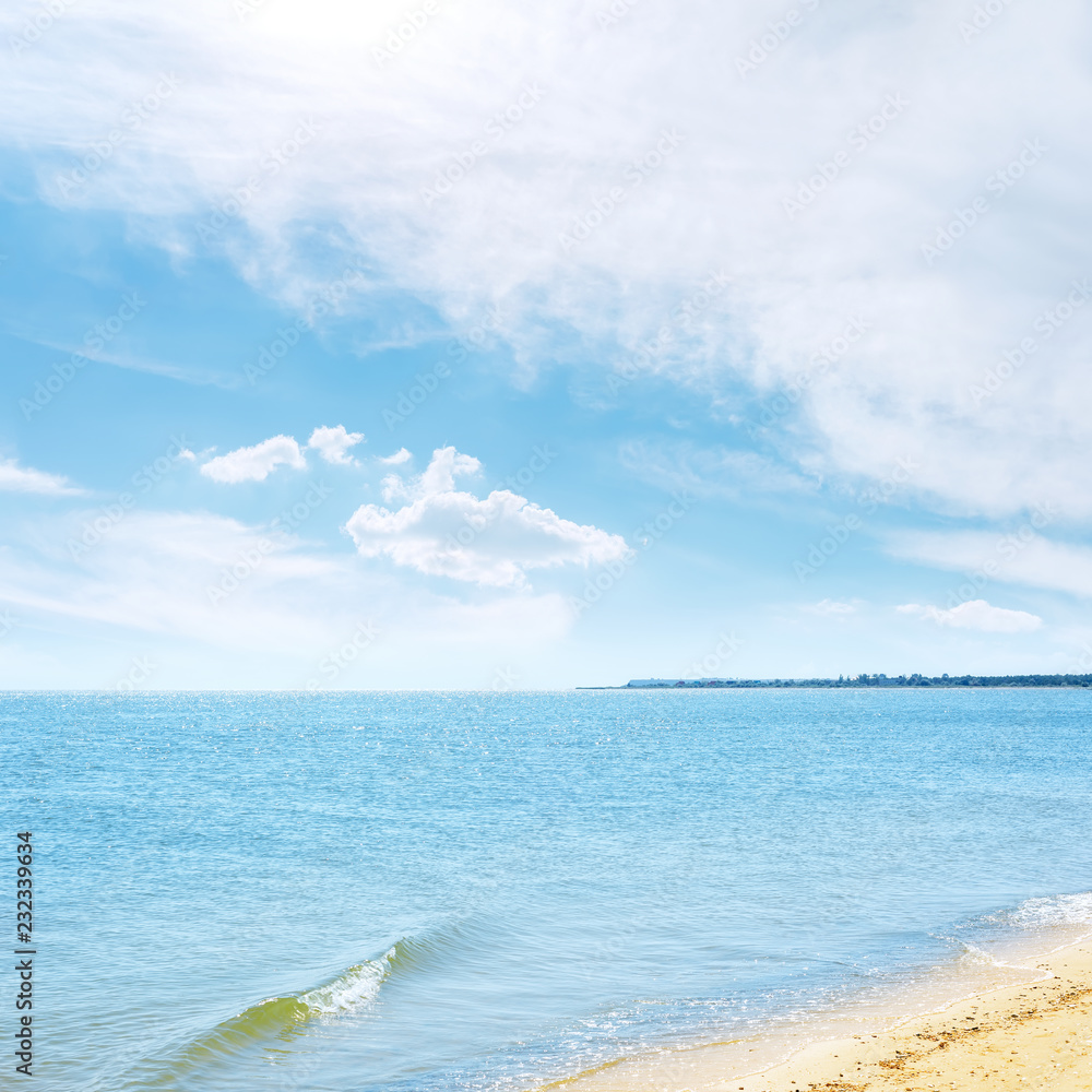 Obraz premium blue sky in white clouds over sea and sand