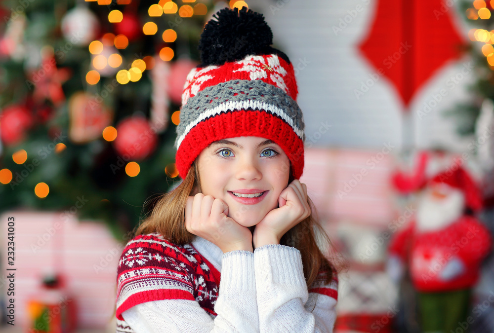 portrait of a beautiful 9-year-old girl in a knitted red hat in a New Year's interior portrait of a beautiful 9-year-old girl in a knitted red hat in a New Year's interior