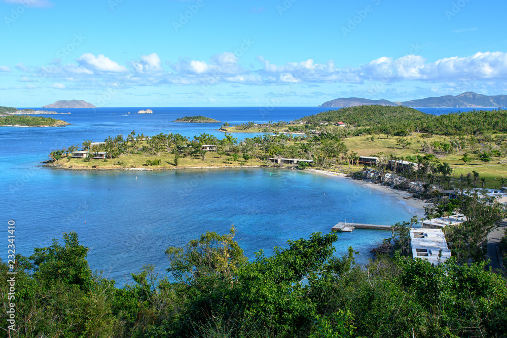 View of the blue lagoon of a tropical island. Green trees, blue sea and blue sky with clouds