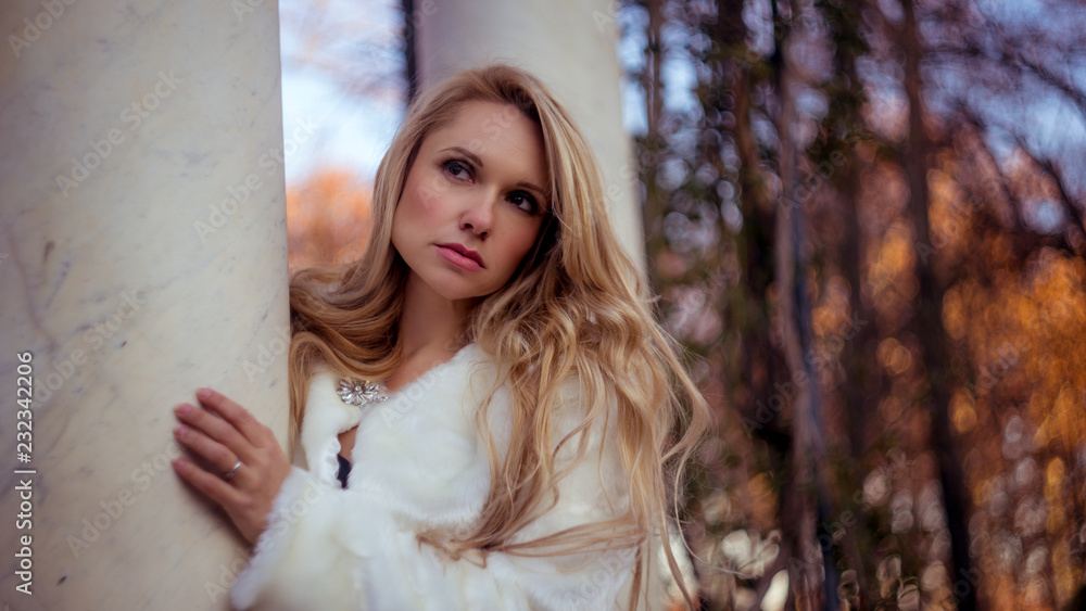 Fototapeta premium melancholy falling, scene of autumn and winter, beautiful blond woman with gestures of melancholy dressed in grey coat