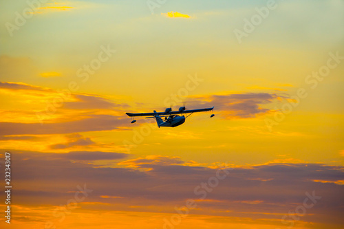 Seaplane with two propellers on the wings against the sky at sunset.