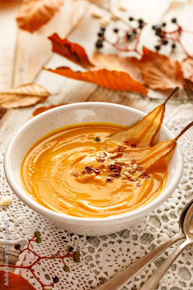 Pumpkin soup with the addition of pear chips in a white ceramic bowl. Delicious and healthy vegetarian soup Pumpkin soup with the addition of pear chips in a white ceramic bowl. Delicious and healthy vegetarian soup