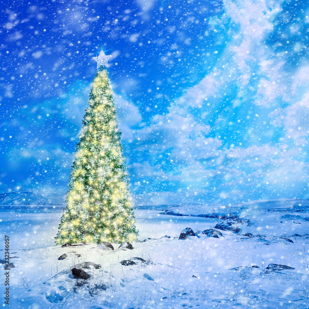 Decorated Christmas tree with colorful lights and ornaments  on snow covered landscape
