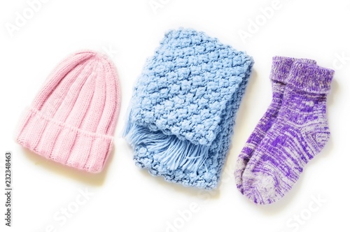 Stylish warm and comfy knitwear. Flat lay winter fashion. Pink wool hat, blue knitted scarf and purple fluffy socks