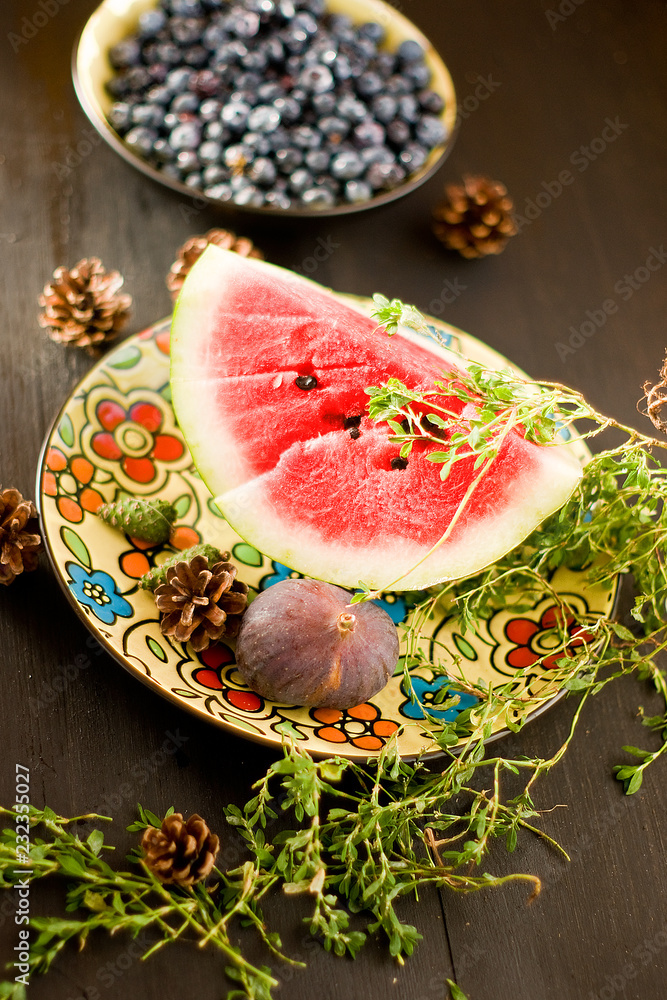 A piece of watermelon with Blueberry and herbs on wooden background A piece of watermelon with Blueberry and herbs on wooden background