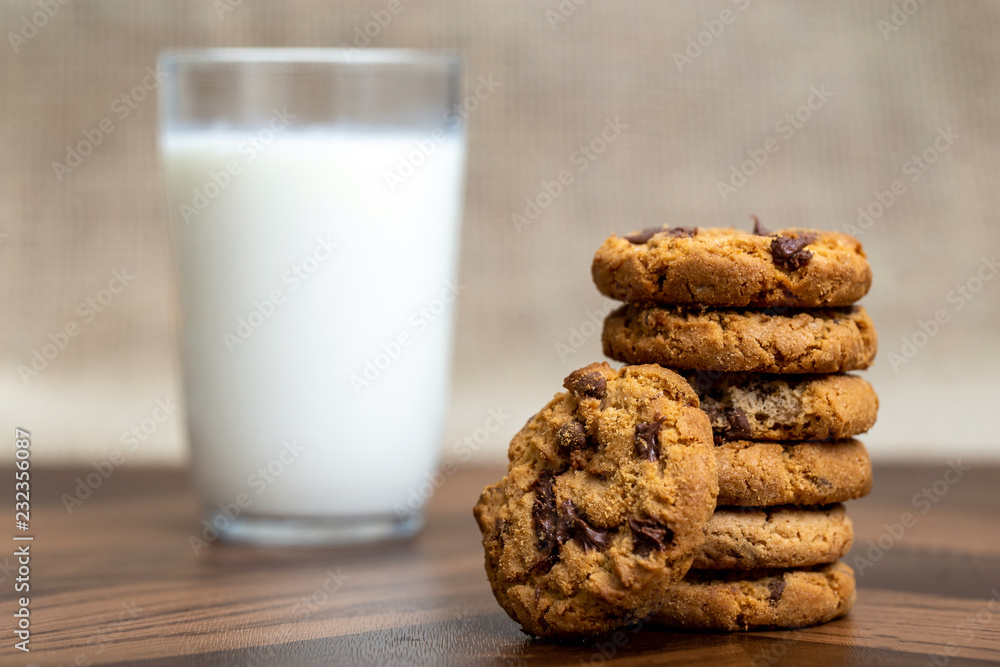 Tasty cookie with creamy chocolate drops, with a glass of milk defocused in the background. Tasty cookie with creamy chocolate drops, with a glass of milk defocused in the background.