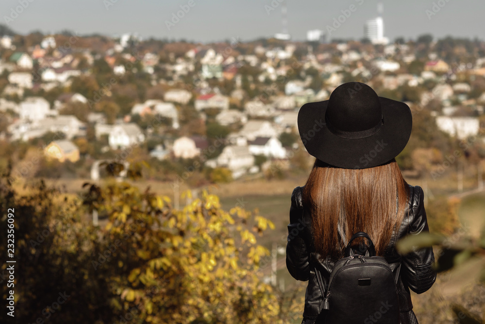 woman with backpack is looking at the city in autumn day woman with backpack is looking at the city in autumn day