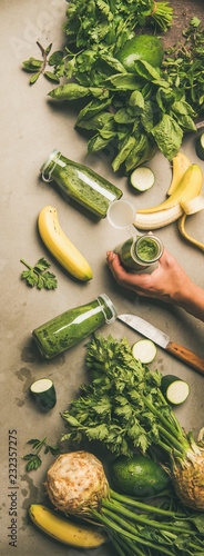 Making green detox smoothie. Flat-lay of ingredients for making smoothie drink and female hands with bottle over concrete background, top view. Clean eating, weight loss food concept