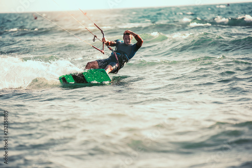 Professional kiter makes the difficult trick on a beautiful background. Kitesurfing Kiteboarding action photos man among waves quickly goes
