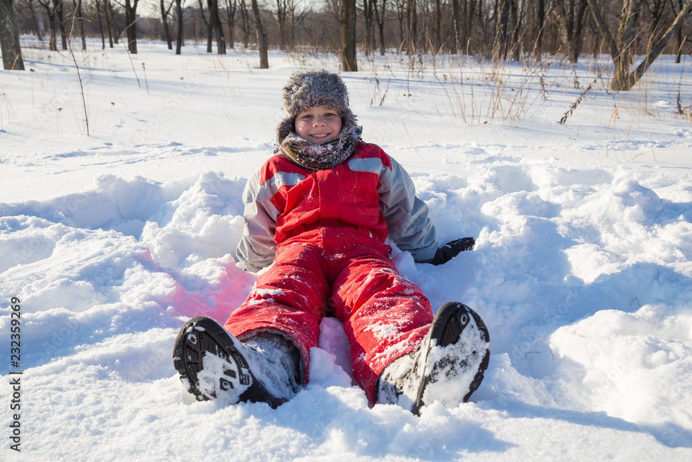 Smiling boy sitting at the snow on park Smiling boy sitting at the snow on park