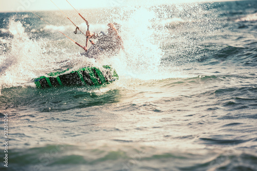 Professional kiter makes the difficult trick on a beautiful background. Kitesurfing Kiteboarding action photos man among waves quickly goes