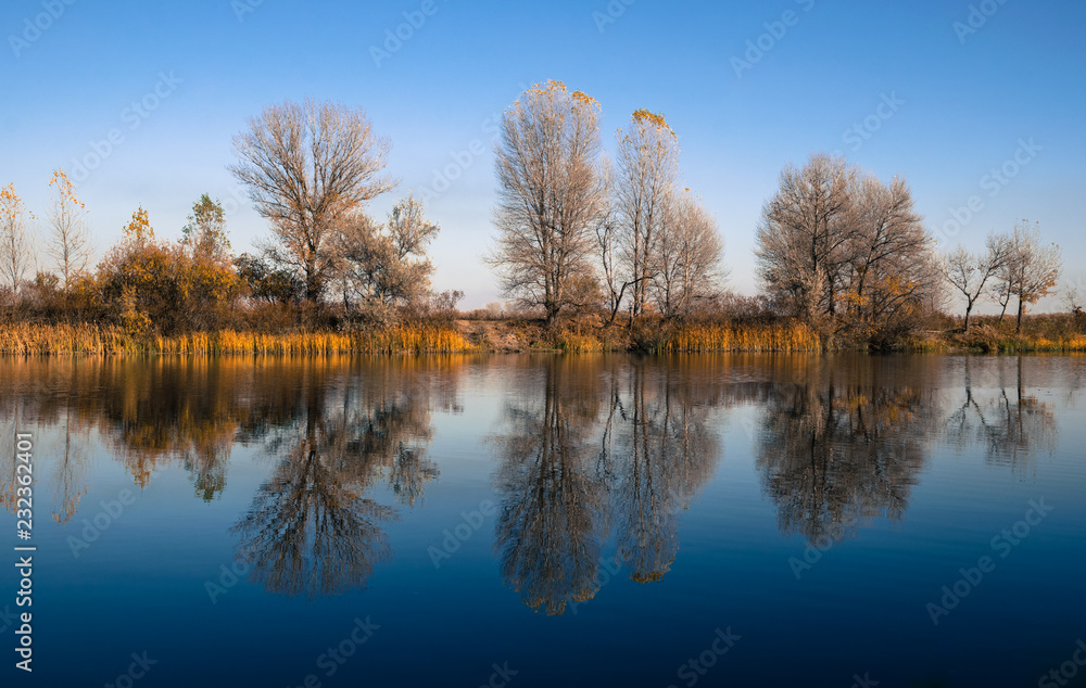 Beautiful autumn landscape. Trees reflected in the water of the lake