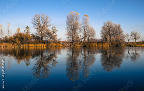 Beautiful autumn landscape. Trees reflected in the water of the lake
