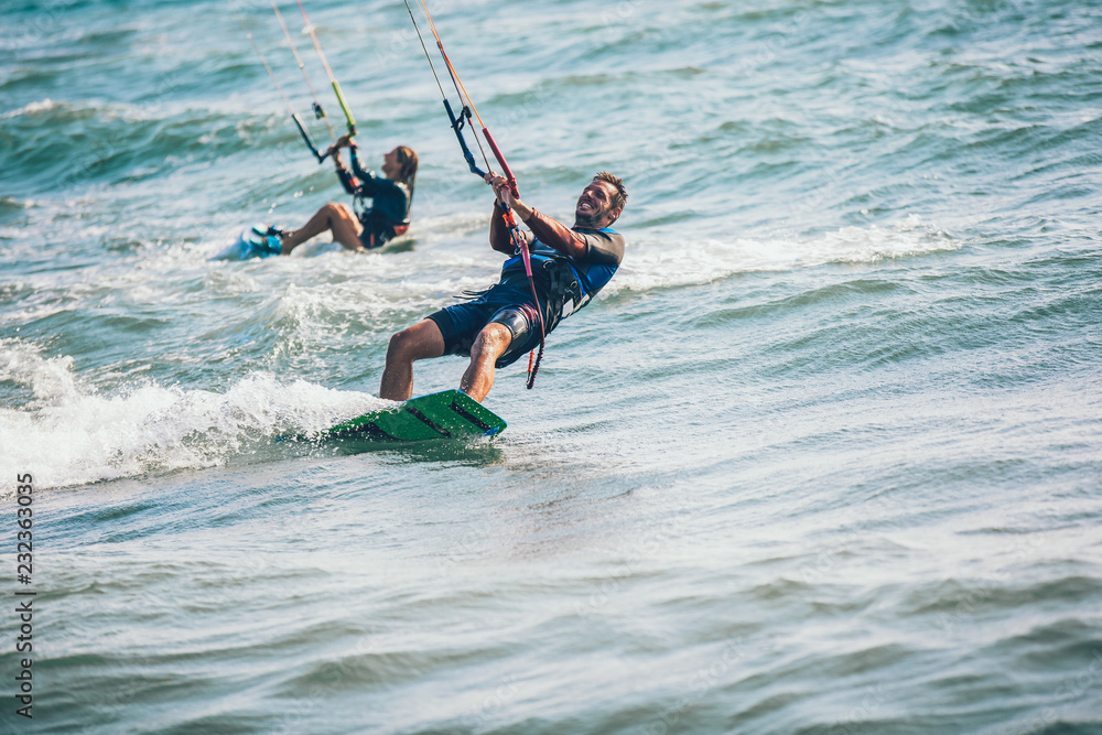 Professional kiter makes the difficult trick on a beautiful background. Kitesurfing Kiteboarding action photos man among waves quickly goes