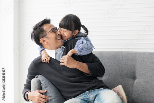 Asian father and daughter playing and kiss together in livingroom at home.