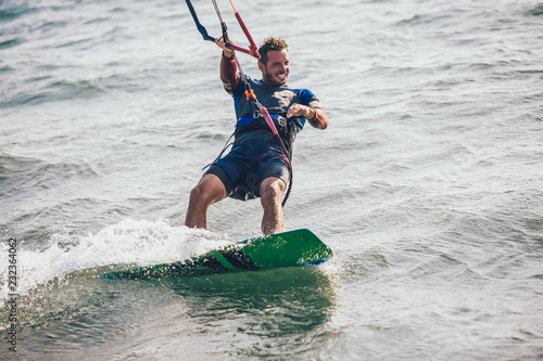 Professional kiter makes the difficult trick on a beautiful background. Kitesurfing Kiteboarding action photos man among waves quickly goes