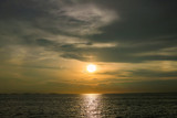 Bright sunset with large yellow sun under the sea surface. Sunset over sea landscape. Beautiful sunset with sky over calm sea in tropical island